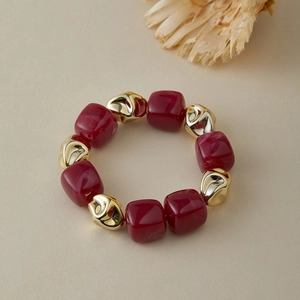 Détail de perles en résine bordeaux et perles métalliques dorées sur le bracelet