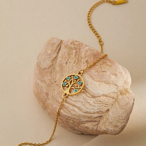 Gold stainless steel tree of life bracelet with blue hearts on a natural stone background