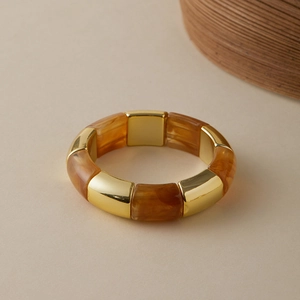 Detail of stretch bracelet with polished gold cubes and amber resin textures