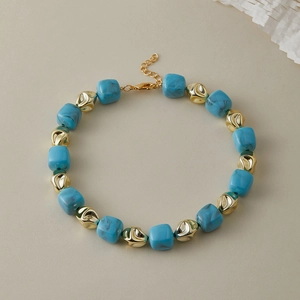Dettagli delle perle in resina blu e delle perle dorate sulla collana girocollo alla moda