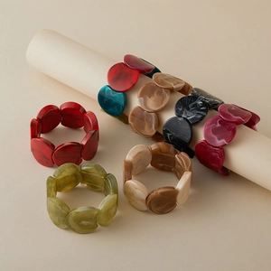 Vue détaillée de larges bracelets en acrylique avec texture marbre ambre et perles géométriques
