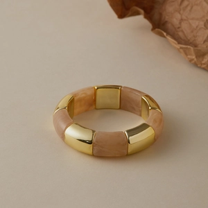 Detailed shot of marbled resin segments and gold-tone metal spacers on a wide bangle