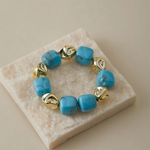 Détail de perles cubiques en résine marbrée bleue et perles dorées sur pierre
