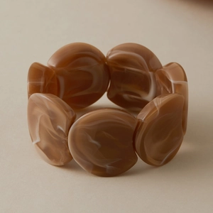 Gros plan sur la texture marbrée ambre des perles en acrylique du bracelet élastique chic
