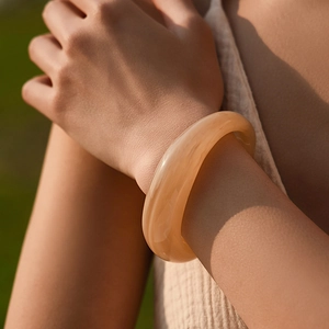 Dettaglio del bracciale in resina ambrata marmorizzata con trama ondulata liscia
