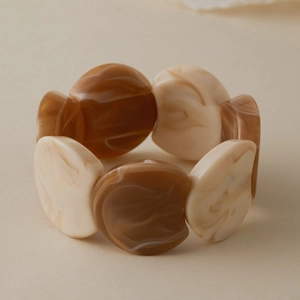 Détail du bracelet en acrylique ambré montrant des perles marbrées sur un fil élastique