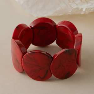 Détail macro d'un large bracelet en acrylique rouge avec des motifs marbrés noirs