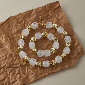 Parure rétro avec perles en métal doré et résine blanche sur fond de papier vintage