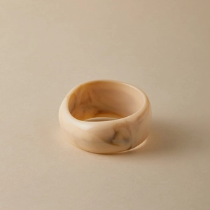 Detailed macro shot of cream acrylic bangle with elegant brown marble resin texture