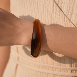 Dettaglio del bracciale in resina ambrata traslucida con finitura lucida e toni miele