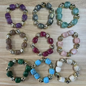 Vue de bracelets en perles de résine en neuf couleurs avec des sphères en métal doré texturé