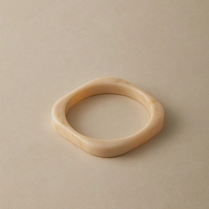 Detailed close-up of cream acrylic bangle with vintage brown textures and square design
