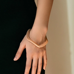 Dettaglio del bracciale in acrilico a onde irregolari ambrato indossato su abiti neri
