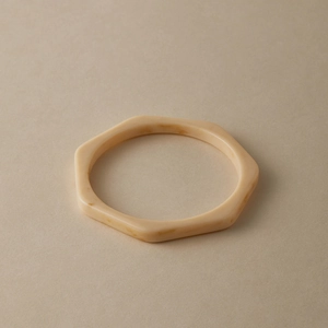 Close-up of hexagonal cream acrylic bangle with marble texture and smooth resin finish