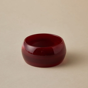 Gros plan du bracelet large en acrylique rouge foncé avec finition lisse et translucide