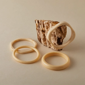 Macro detail of geometric acrylic bangles on a textured stone display background