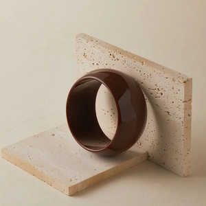Vue macro d'un large bracelet manchette en résine marron sur pierre beige