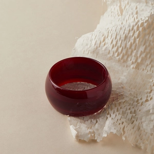 Vue macro d'un large bracelet en acrylique rouge foncé avec finition brillante