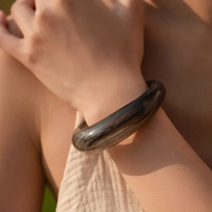 Dettaglio di un bracciale in resina grigio fumo traslucido indossato su un polso