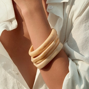 Classic cream acrylic thick bangles set with marble texture worn by a model in sunlight