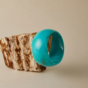 Gros plan d'un large bracelet en acrylique turquoise avec texture marbrée brune sur pierre