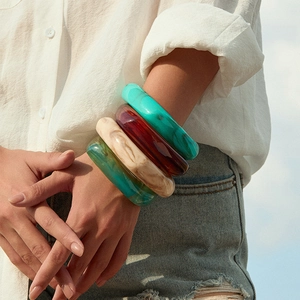 Geometrische brede acryl armband met kleurrijke marmerpatronen om de pols van een vrouw