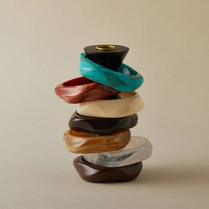 Detailed stack of irregular acrylic resin bangles with marble and amber textures on a stand