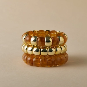 Dettaglio del set di tre bracciali bohémien con perle dorate e resina ambrata lucida