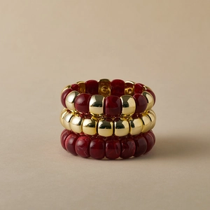 Dettaglio del set di tre braccialetti bohémien con metallo dorato e perle in resina rossa