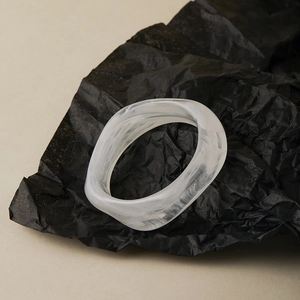Macro detail of the twisted wavy resin bangle featuring black and white marble ink patterns