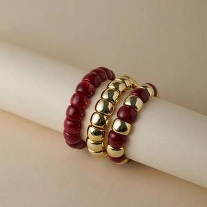 Dettaglio del set di bracciali boho a tre strati con resina rosso vino e perline d'oro