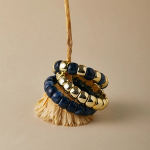 Dettaglio di tre bracciali elastici stile boho con perle in resina blu navy e dorate