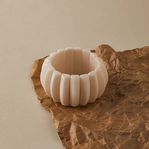 Detailed close-up of a wide cream pink resin beaded bracelet on a textured background