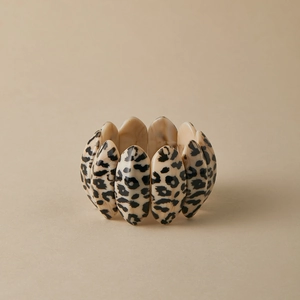 Macro detail of elastic leopard print acrylic bracelet with glossy cream resin links