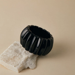 Detailed view of wide black acrylic beaded elastic bracelet on natural stone base