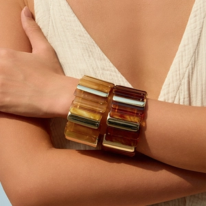 Gros plan de bracelets larges en résine aux motifs ambre et écaille avec accents dorés