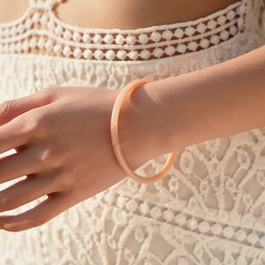 Vue détaillée d'un bracelet en résine rose translucide avec un tissu en dentelle blanche