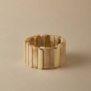 Détail d'un bracelet extensible large avec tuiles en résine marbrée et plaques en métal doré