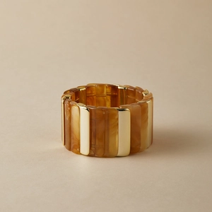 Vue détaillée du bracelet large élastique avec résine ambrée et segments en métal doré poli