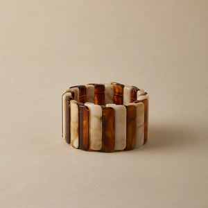 Détail d'un large bracelet en résine avec des maillons ambre écaille et crème marbré