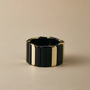 Détail du bracelet élastique large avec segments rectangulaires polis noirs et dorés