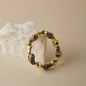 Macro view of leopard print resin beads and polished golden organic drops on the bracelet