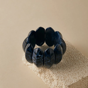 Detailed shot of dark blue marble resin stretch bracelet on a textured stone stand