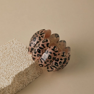 Macro detail of elastic leopard print acrylic bracelet resting on natural mineral stone