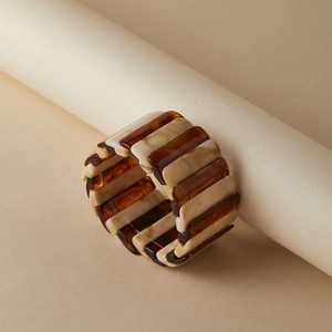 Gros plan d'un bracelet élastique en résine ambre et marbre sur support
