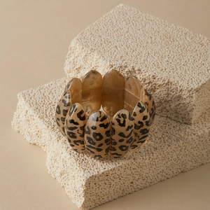 Detailed close-up of leopard print resin stretch bracelet on natural beige stone