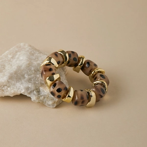 Macro view of leopard print resin beads and gold-tone metal spacers on an elastic bracelet