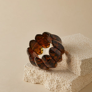 Detail of leopard print wide elastic bracelet on beige stone textured background