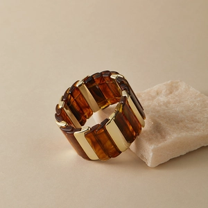 Détail d'un large bracelet extensible en résine ambre et blocs de métal doré poli