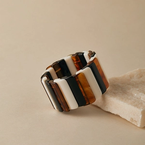 Détail d'un large bracelet élastique avec segments en résine noire et ambre sur pierre